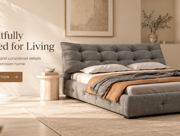 Magico Home bedroom hero banner featuring a grey upholstered bed in a warm minimalist interior